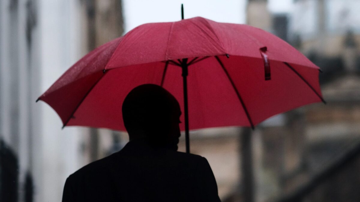 homme tenant un parapluie rouge