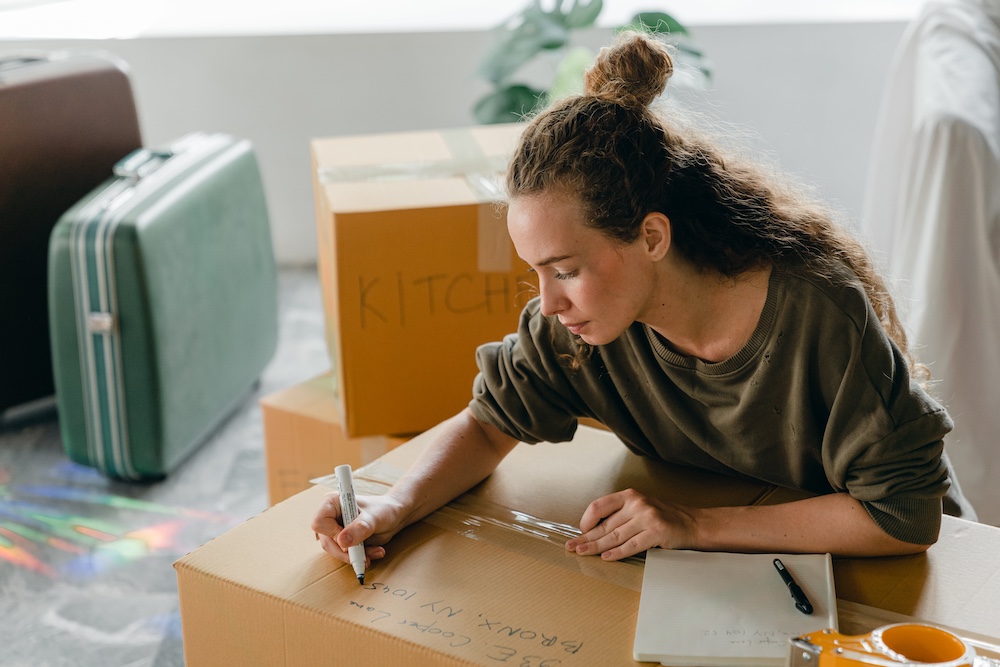 femme écrivant sur une boite de déménagement